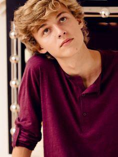 a young man with curly hair wearing a purple shirt