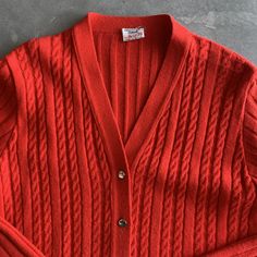 "Red cardigan long length with front pockets Construction: Stitched overlock at seams, front patch pockets, v neck with buttons, over the hip length Fabric: Orlon Acrylic knit / Lightweight but warm, washable, decreased wrinkles Tags: St Micheal Orlon / size 16 to fit 38\" bust / Made in Britain Condition: very good except missing buttons. missing 3 but extra one on side seam so missing 2, some minor pilling Size: Medium 38\" Bust c1970s, 1960s Measures: Shoulders: 17.5\" Bust: 38\" Waist: 34\" Red V-neck Cardigan For Work, Vintage V-neck Cardigan For Layering, Red V-neck Sweater With Button Closure, Red V-neck Outerwear With Button Closure, Classic Red V-neck Sweater For Fall, Red Knit V-neck Cardigan, Red V-neck Knit Cardigan, Red Knit Cardigan With Button Closure, Classic Red Outerwear For Layering