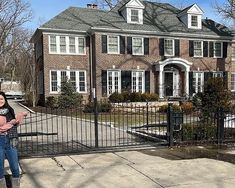 a woman standing in front of a large brick house