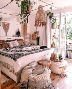 a large bed sitting inside of a bedroom next to a tall plant potted tree