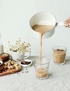 a person pours coffee into small cups on a table with flowers and other ingredients