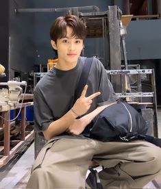 a young man sitting on top of a chair giving the peace sign