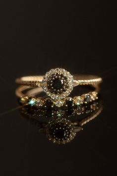 a close up of a diamond ring on a black surface with reflections in the background