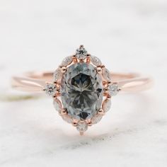 an oval gray diamond surrounded by white and rose gold halos on top of a pink gold band