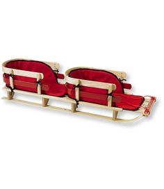 two red chairs sitting on top of a wooden sleigh next to each other