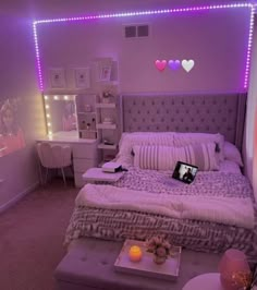 a bed room with a neatly made bed next to a night stand and purple lights