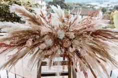 an arrangement of dried flowers and feathers on a table in front of a cityscape