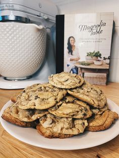 a pile of cookies sitting on top of a white plate next to a cookbook