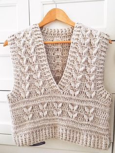 a knitted sweater hanging on a wooden hanger in front of a white door