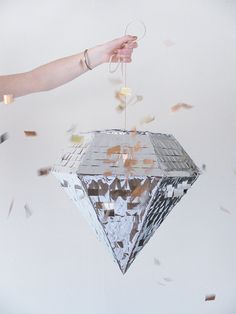 a person holding a string attached to a piece of tin foil with confetti falling from it