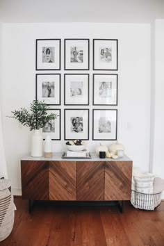 a white room with pictures on the wall and a wooden cabinet in front of it