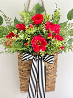 a basket filled with red flowers and greenery