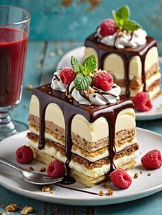 two desserts on plates with raspberries and chocolate drizzle