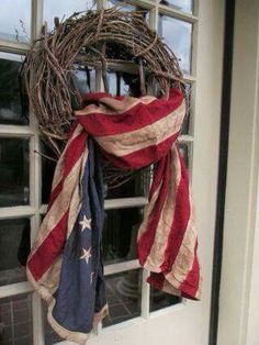 a wreath with an american flag hanging on the side of a door, in front of a window