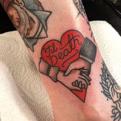 a person with tattoos on their legs holding a heart