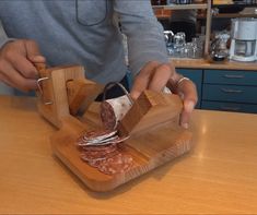 a person cutting meat with a knife and fork on a wooden table in a kitchen