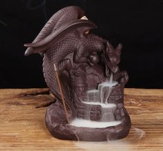 an incense burner made to look like a dragon with a hat on its head