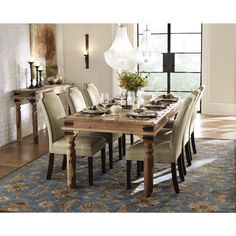 a dining room table and chairs in front of a large window with an area rug on the floor