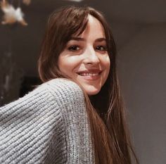 a woman with long brown hair smiling at the camera