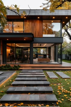 a modern house with stairs leading to the front door and patio area, surrounded by green grass