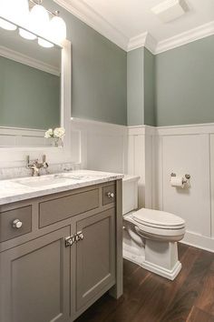 a white toilet sitting under a bathroom mirror next to a sink in a bath room