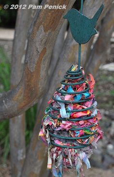 a bird decoration hanging from a tree with colorful ribbons on it's back end