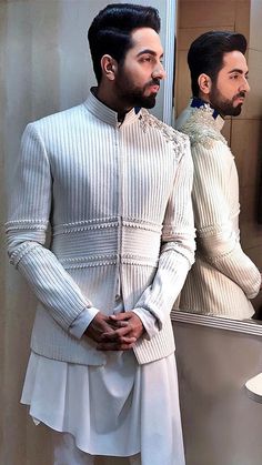 a man standing in front of a bathroom mirror wearing a white outfit with ruffles