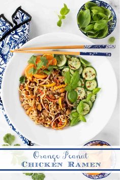 a white bowl filled with noodles and vegetables next to chopsticks on a blue and white plate