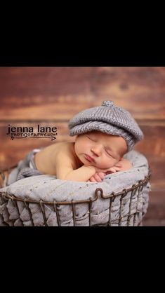 a baby sleeping in a basket wearing a hat