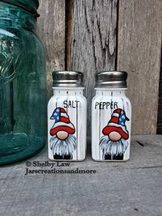 two salt and pepper shakers with an american flag hat on them next to a mason jar