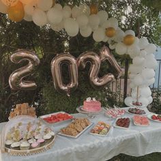 a table topped with lots of desserts and balloons in the shape of numbers 2013