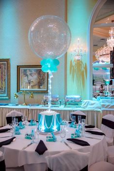 a table set up for a party with black and white linens, blue decorations and balloons