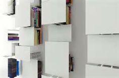 the bookshelf is made out of white cubes and has many different colored books on it