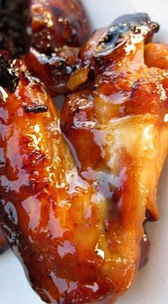 three pieces of chicken sitting on top of a white plate covered in bbq sauce