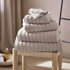 a stack of folded towels sitting on top of a wooden stool