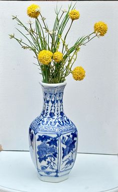 a blue and white vase with yellow flowers in it