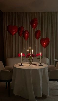 a table with candles and red heart balloons