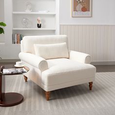 a living room with a white chair and coffee table in front of a bookshelf