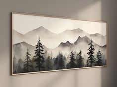 a painting hanging on the wall above a chair in front of a window with mountains and trees