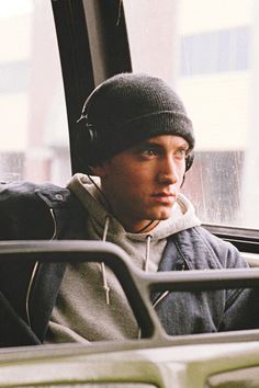 a young man wearing headphones sitting on a bus