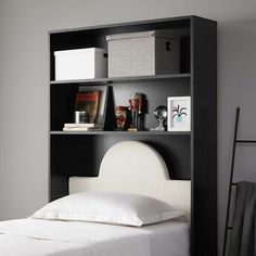 a black bookcase with white sheets and pillows