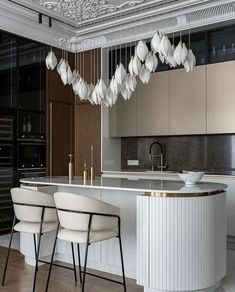 an elegant kitchen with marble counter tops and white chairs, gold accents on the ceiling