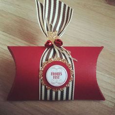 a red and black striped gift bag with a ribbon around it's edge on a wooden table