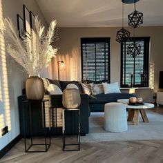 a living room filled with lots of furniture next to a tall window covered in blinds