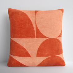 an orange and white pillow with circles on the front, sitting on a table next to a gray wall