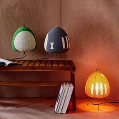 three lamps sitting next to each other on top of a wooden table in front of a wall