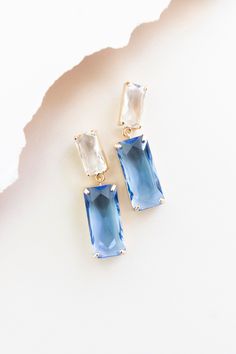 two pairs of blue and white earrings sitting on top of a piece of parchment paper