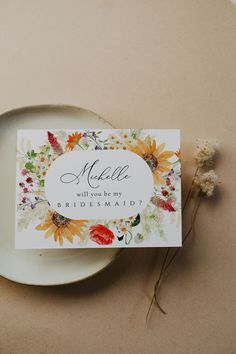 a plate with a place card on it next to a flower arrangement and a small plant