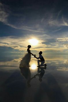 a bride and groom holding hands in front of the sun