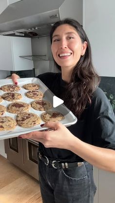 a woman holding up a tray of cookies